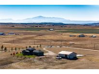 Aerial view of house, barn, and expansive land with mountain backdrop at 26100 County Road 5, Elizabeth, CO 80107