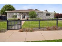 Charming gray brick home with well-manicured lawn, inviting front porch, and a decorative sunflower wreath at 2945 E 26Th Avenue Pkwy, Denver, CO 80205
