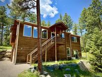 Beautiful two-story home featuring a wooden exterior, open deck, and mature trees surrounding the property at 6752 S Columbine Rd, Evergreen, CO 80439