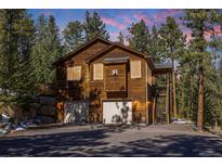 Beautiful two-story home featuring a two-car garage and a surrounding forest at 6752 S Columbine Rd, Evergreen, CO 80439