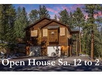 Charming two-story brown home with two-car garage nestled among mature evergreen trees at 6752 S Columbine Rd, Evergreen, CO 80439