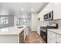 Bright kitchen features stainless appliances, white cabinets, and island with sink at 1464 Orchard St, Brighton, CO 80601