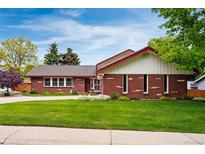 Charming brick home featuring a well-maintained lawn and colorful landscaping, complemented by a classic tile roof at 3608 S Newport Way, Denver, CO 80237