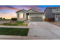 Charming home featuring a well-manicured lawn and a beautiful stone-accented facade, set against a vibrant sunset at 581 Park Blvd, Brighton, CO 80603