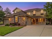 Charming two-story home featuring stone accents, a manicured lawn, and a welcoming porch at 24422 E Frost Dr, Aurora, CO 80016