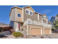 Tan and brown two-story townhouse with attached garages and a charming front porch at 2673 Live Oak Ct, Castle Rock, CO 80104