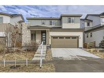 Two-story home featuring a beige and green exterior, a two-car garage, and a stone pillar accent at 17189 E 103Rd Pl, Commerce City, CO 80022
