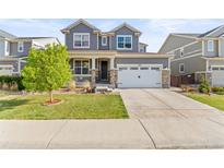 Charming gray two-story home featuring a well-manicured front lawn and a two car garage with stone accents at 7018 E 123Rd Pl, Thornton, CO 80602