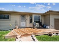 Inviting front porch with wood deck, chairs, and a bay window, creating a welcoming entrance to this charming residence at 9508 Lou Dr, Northglenn, CO 80260