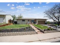 Charming single-story home featuring a well-maintained lawn and inviting curb appeal with a brick retaining wall and landscaping at 9508 Lou Dr, Northglenn, CO 80260