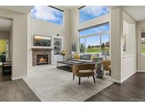 Bright living room featuring a stone fireplace, large windows with beautiful views, and comfortable seating at 22665 E Calhoun Pl, Aurora, CO 80016