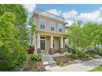 Inviting two-story home with a charming front porch and rooftop balcony, surrounded by lush greenery at 11346 E 27Th Ave, Denver, CO 80238