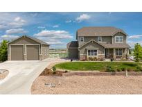 Charming two-story home boasts a separate garage and landscaped front yard on a sunny day at 11343 E 163Rd Ct, Brighton, CO 80602