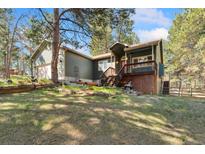Charming home with a lush green lawn, mature trees, and inviting elevated wood front porch entry at 34103 Forest Park Dr, Elizabeth, CO 80107