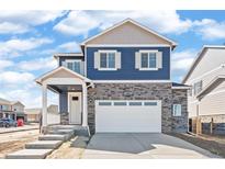 Charming two-story home with blue siding, stone accents, a covered porch, and a two-car garage at 18120 Dandy Brush Ln, Parker, CO 80134