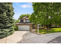 Charming two-story home featuring a two-car garage, stone accents, and mature trees in a well-manicured front yard at 9174 Lark Sparrow Pl, Highlands Ranch, CO 80126