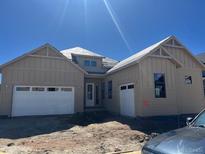 Tan home featuring a two car garage and a covered entrance on a sunny day at 901 Coal Bank Trl, Castle Rock, CO 80104