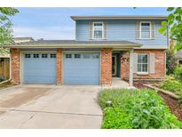 Charming blue two-story home with a brick facade and a two car garage at 11404 W Sharkstooth Peak, Littleton, CO 80127