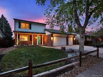 Charming two-story home with a well-manicured lawn, brick accents, and a three-car garage at dusk at 13935 E Idaho Pl, Aurora, CO 80012