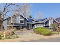 Charming home with solar panels, gray siding, brick accents, mature landscaping, and a spacious driveway at 1413 Ben Nevis Ave, Broomfield, CO 80020