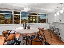 Bright dining area features hardwood floors, a stylish rug, and large windows with beautiful city views at 1891 Curtis St # 1820, Denver, CO 80202
