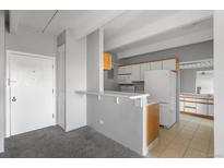 Compact kitchen featuring white cabinets, appliances, and a breakfast bar perfect for casual dining at 1888 S Jackson St # 604, Denver, CO 80210