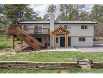 Charming two-story home featuring a wooden deck, inviting entryway, and lush green lawn at 721 Forest View Rd, Monument, CO 80132