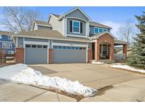 Charming two-story home with a brick-accented entryway and a spacious three-car garage at 7065 Campden Pl, Castle Pines, CO 80108