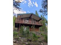 Rustic home with a spacious balcony, nestled amongst lush trees and foliage at 542 Harris Dr, Idaho Springs, CO 80452