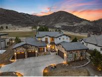 Stunning home exterior with stone accents, tile roof, three-car garage, and beautiful mountain views at sunset at 8033 Galileo Way, Littleton, CO 80125