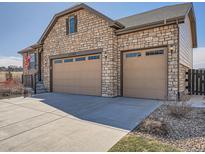 Stunning stone exterior featuring a three car garage and well maintained landscaping at 23709 E Caleb Pl, Aurora, CO 80016