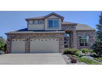 Two-story brick home featuring a large two car garage, manicured yard, and charming architectural details at 973 Orion Way, Castle Rock, CO 80108