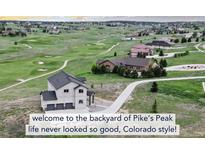 Stunning aerial view of a modern home on a golf course with mountain views at 19887 Kershaw Ct, Monument, CO 80132