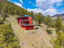 Stunning red modern home nestled into the mountain, boasting balconies and breathtaking views at 5896 Peregrine Trl, Golden, CO 80403