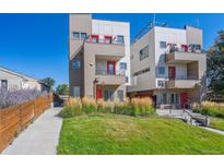 Modern multi-level townhouse with red accents, landscaped front yard, and walkway under clear blue sky at 1216 Perry St, Denver, CO 80204
