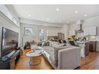 Bright living room featuring a spacious couch, hardwood floors, and an open concept kitchen at 1216 Perry St, Denver, CO 80204