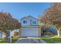 Charming blue two-story home with a gray garage door, brick accents, and well-manicured lawn at 11580 Depew Ct, Westminster, CO 80020