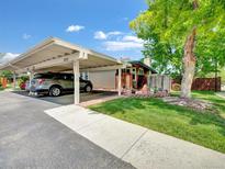 View of the carport with parking and landscaping with mature trees and well-maintained lawn at 8730 E Roundtree Ave, Greenwood Village, CO 80111
