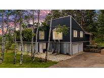 Two-story home with black siding, light gray trim, stone patio and two-car garage at 8783 S Ault Ln, Morrison, CO 80465