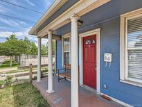 Charming front porch with white columns, a red front door and a bench provides a cozy entrance to the home at 66 E 45Th Ave, Denver, CO 80216