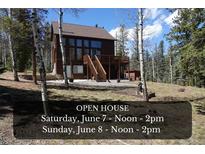 Charming exterior view of home with deck and stairs surrounded by forest and hosting an open house at 10438 Sunlight Ln, Conifer, CO 80433