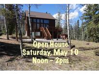 Charming home featuring a wooden deck and large windows, surrounded by trees at 10438 Sunlight Ln, Conifer, CO 80433