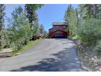 Charming multi-story home with an attached garage and a long, sloping driveway surrounded by trees at 10438 Sunlight Ln, Conifer, CO 80433