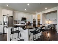 Bright kitchen boasts white cabinetry, a central island with bar seating, and modern stainless steel appliances at 16062 Red Bud Loop, Parker, CO 80134