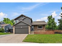 Charming two-story home featuring a well-maintained lawn, brick accents, and a spacious two-car garage in a quiet neighborhood at 10859 W Fair Ave, Littleton, CO 80127