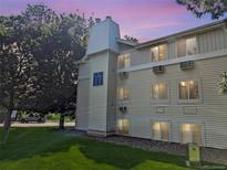 Low angle view of a tan apartment building on a green lawn, with trees and a dusk sky at 17361 E Mansfield Ave # 532R, Aurora, CO 80013