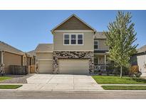 Two-story home boasts a well-maintained lawn, two car garage and a blend of stone and siding accents at 12734 E 104Th Pl, Commerce City, CO 80022