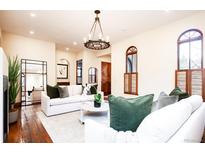 Bright living room with hardwood floors, white sofas, decorative chandelier and arched windows with wooden shutters at 2435 S Milwaukee St, Denver, CO 80210