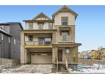 Stylish three-story home with a stone and siding exterior, inviting front porch, and an attached two-car garage at 8867 Waterleaf Ln, Littleton, CO 80125