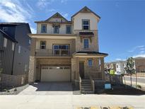 Beautiful three-story home with stone and siding, attached two-car garage, and covered balcony at 8867 Waterleaf Ln, Littleton, CO 80125